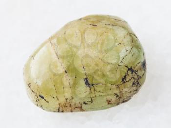 macro shooting of natural mineral rock specimen - polished green beryl gem stone on white marble background