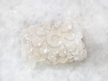 macro shooting of natural mineral rock specimen - raw crystal of Prehnite stone with Okenite on white marble background from Pune district, India