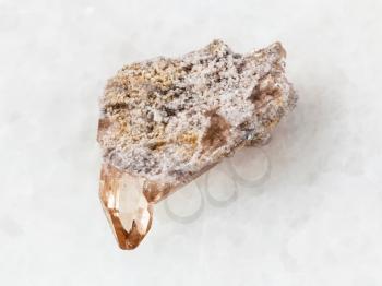 macro shooting of natural mineral rock specimen - crystal of topaz stone on white marble background from Brazil