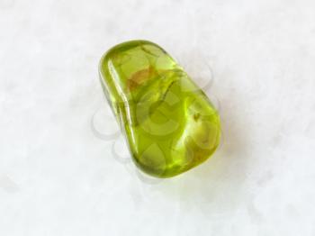 macro shooting of natural mineral rock specimen - polished Peridot gem stone on white marble background from Pakistan