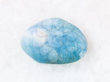 macro shooting of natural mineral rock specimen - polished aquamarine (blue beryl) gem stone on white marble background from Brazil