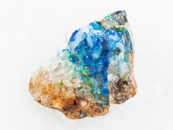 macro shooting of natural mineral rock specimen - tennantite crystal, green Tyrolite and blue Azurite on rough quartz stone on white marble background from Ural Mountains, Russia