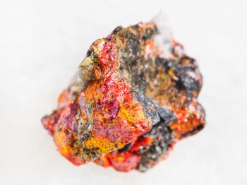 macro shooting of natural mineral rock specimen - rough Realgar crystals on stone on white marble background from Luhumi mine, Georgia