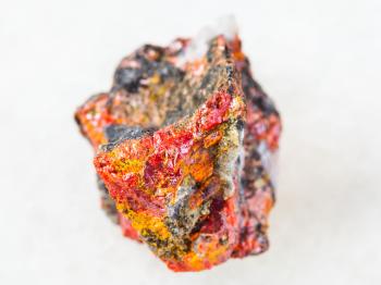 macro shooting of natural mineral rock specimen - raw Realgar crystals on stone on white marble background from Luhumi mine, Georgia