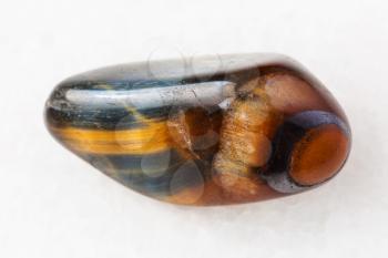 macro shooting of natural mineral rock specimen - tiger's eye and hawk's eye gemstone on white marble background from South Africa