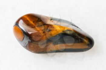 macro shooting of natural mineral rock specimen - polished tiger's eye and hawk's eye gemstone on white marble background from South Africa