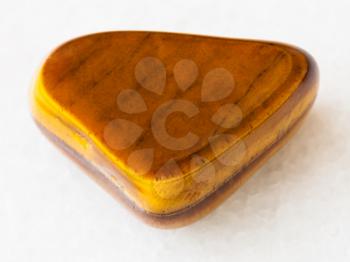 macro shooting of natural mineral rock specimen - polished tiger-eye gem stone on white marble background from South Africa