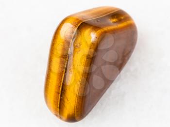 macro shooting of natural mineral rock specimen - tiger-eye gem stone on white marble background from South Africa