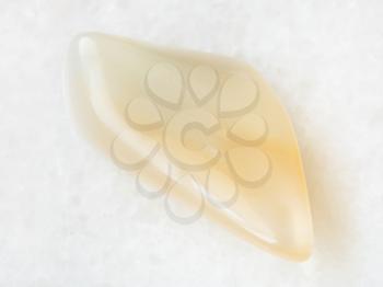 macro shooting of natural mineral rock specimen - yellow moonstone (adularia) gemstone on white marble background