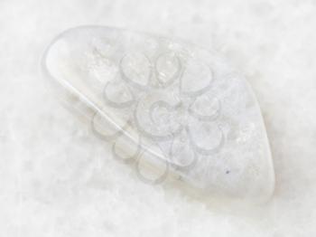 macro shooting of natural mineral rock specimen - tumbled white moonstone (adularia) gemstone on white marble background
