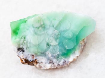 macro shooting of natural mineral rock specimen - raw crystal of Chrysoprase gemstone on white marble background from Kazakhstan