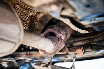 repairing of corrugation muffler of exhaust system in car workshop - bottom view of old broken muffler on car