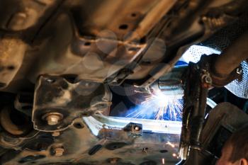 repairing of corrugation muffler of exhaust system in car workshop - welder welds the silencer on car by argon welding