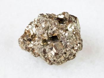 macro shooting of natural rock specimen - rough iron pyrite (fool's gold) stone on white marble background