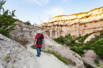 Travel to Turkey - tourist on rock slope in gorge near Goreme town in Cappadocia in spring