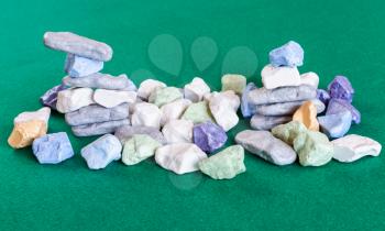 stacks and pile from various multicolored stones on green baize table