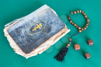 old psalm book, worry beads and three wooden dices on green baize table