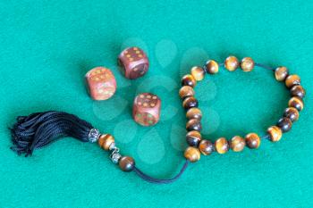 worry beads (komboloi) and three wooden dices with six points on green baize table