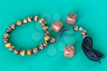 worry beads and three wooden dices with various points on green baize table