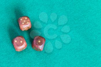 top view of three wooden dices with various points on green baize table with copyspace