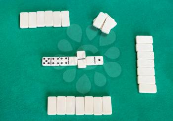 top view of playfield of dominoes board game with white tiles on green baize table