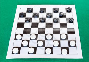 checkers on black and white checkered sheet board on green baize table