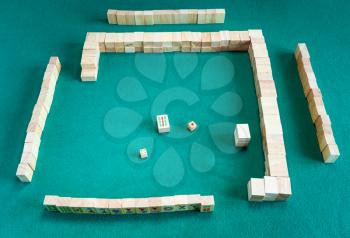 beginning of play of mahjong (disassembling the wall), tile-based chinese strategy board game on green baize table