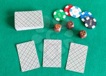 top view of card decks, casino tokens and wooden dices on green baize table