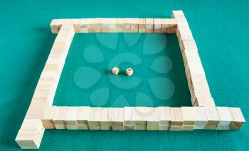 beginning of play in mahjong, tile-based chinese strategy board game on green baize table