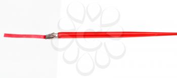 side view of red dip pen drawing a red line on sheet of paper by wide nib isolated on white background