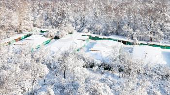 above view of snow-covered garages between urban Timiryazevsky park and apple orchard in Moscow city in sunny winter day