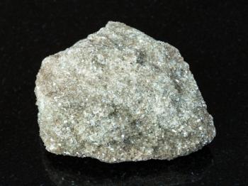 macro shooting of natural mineral - rough muscovite greisen rock on black granite from Ural Mountains