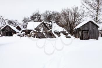 snow-covered old abandoned courtyard in typical russian village in winter day in Smolensk region of Russia