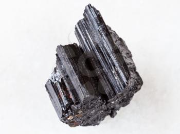 macro shooting of natural rock specimen - rough crystal of black Tourmaline (Schorl) gemstone on white marble background
