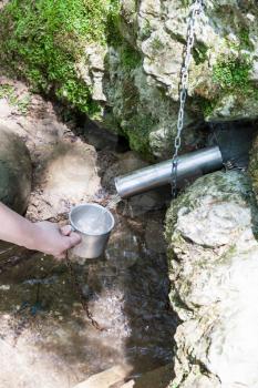 tour to Shapsugskaya anomalous zone - tourist fills the mug with water from Silver Spring (source of Living and Dead water) in Abinsk Foothills of Caucasus Mountains in Kuban region of Russia