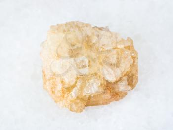 macro shooting of natural mineral - raw Topaz stone on white marble from Ilmenskoe deposit at South Ural Mountains