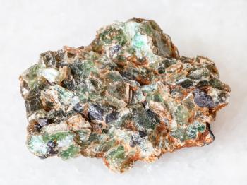 macro shooting of natural mineral - green beryl and emerald crystals in rough rock on white marble from Ural Mountains