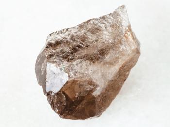 macro shooting of natural mineral - rough smoky quartz crystal on white marble from Ural Mountains
