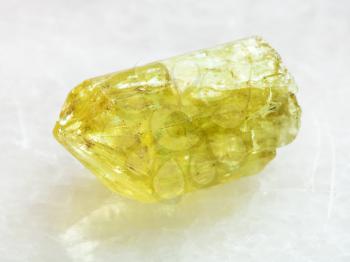 macro shooting of natural rock specimen - rough crystal of yellow Apatite gemstone on white marble background from Mexico