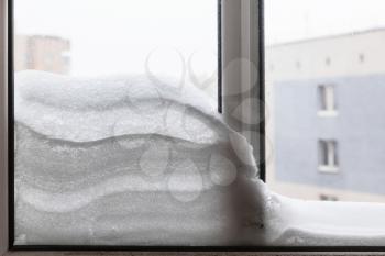 snowdrift between window glasses at home in winter day in Moscow city