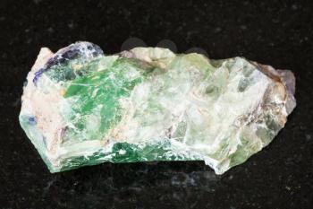 macro shooting of natural mineral - rough green Beryl, Chrysoberyl, Alexandrite gemstone on black granite from Ural Mountains