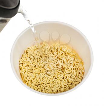 cooking instant noodles - pouring water from kettle into box with dried instant noodles isolated on white background