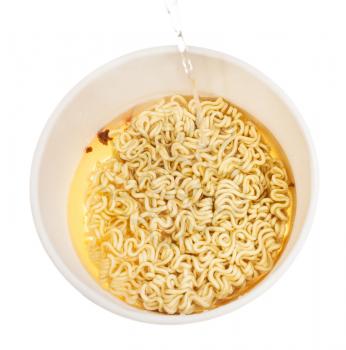 cooking instant noodles - pouring hot water into cup with instant noodles isolated on white background