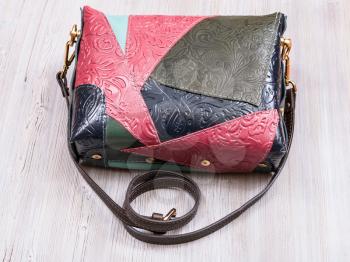 patchwork embossed leather handbag on gray wooden table