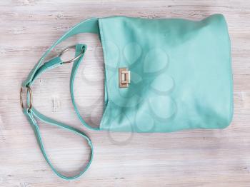 handmade turquoise colour leather crossbody bag on gray wooden table