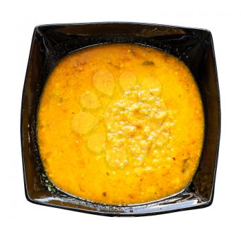 Indian cuisine - yellow Dal Tadka from lentils with curry cooked in home style in black bowl isolated on white background