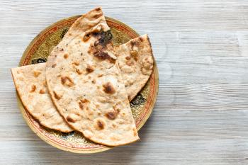 Indian cuisine - Tandoori Roti whole wheat flat bread on brass plate on gray table