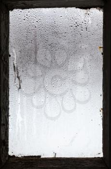water drops from melting snow on surface of misted window in old rural house in winter