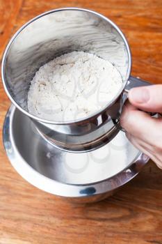 cooking of pie - sifting the flour through steel sifter into bowl