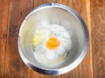 cooking of pie - top view of pile of flour with broken egg in steel bowl
